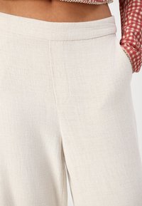 Pantalones cropped de mezcla de lino en color blanco roto con un acabado texturizado, que presentan bolsillos laterales y una cinturilla suave.