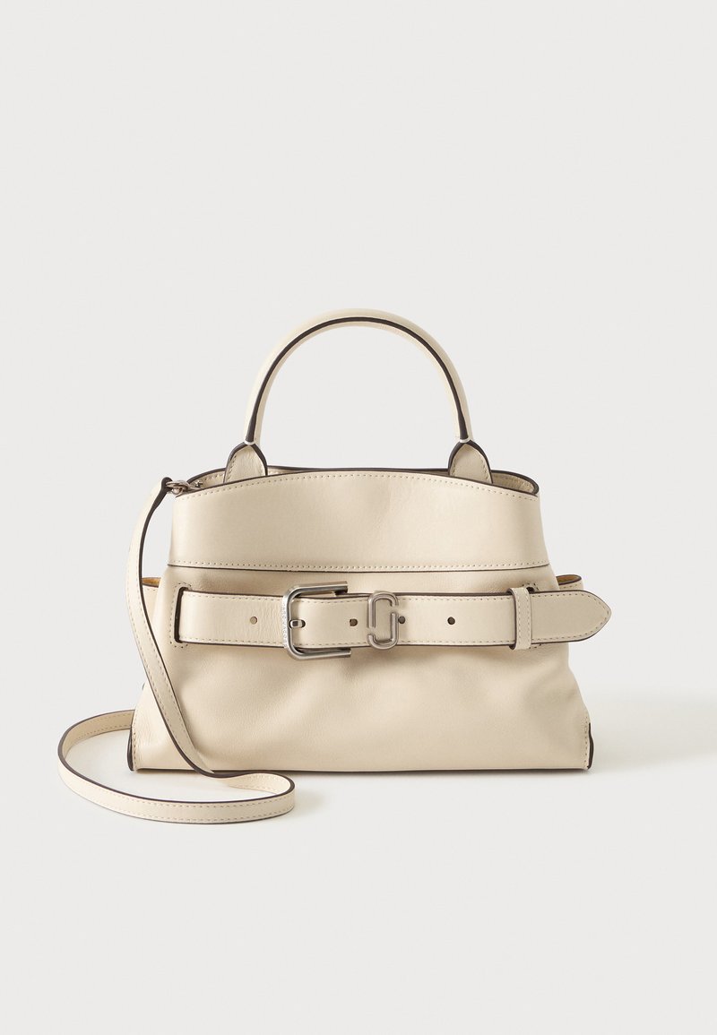 Sac à main en cuir crème avec poignée supérieure, bandoulière réglable et large ceinture avec boucle argentée sur le devant.