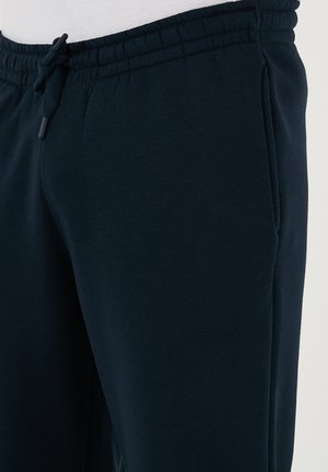 Pantalons de survêtement bleu marine en tissu doux, dotés d'une taille élastique avec cordon de serrage et de poches latérales.