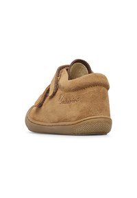Scarpa per bambini in suede marrone con una texture morbida, punta arrotondata e una fascetta in velcro. Presenta una suola in gomma testurizzata e dettagli a cucitura.