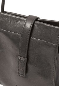 Borsa a tracolla nera in pelle con finitura testurizzata, caratterizzata da un pattino cucito e una cinghia con chiusura a bottone a scatto.