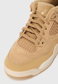 Bež usnjeni športni čevlji z mrežnimi paneli, ravnimi vezalkami in teksturiranim podplatom. Na jeziku in strani imajo logotip v svetlejši bež barvi.