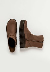 Bottines en cuir brun avec des semelles en plateforme à nervures noires, fermeture éclair latérale et bout arrondi lisse sur fond blanc.