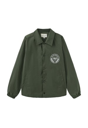 Mørkegrøn jakke med knapper, elastiske manchetter og et hvidt, rundt logo med teksten "Pas de Monaco 911 Club" på venstre bryst.