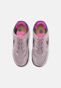 Baskets Nike violettes et roses avec une tige en mesh et en daim, bout arrondi, système de laçage et semelle en caoutchouc texturée.