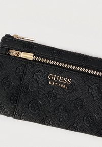 Μαύρο πορτοφόλι με υφή και ανάγλυφο μοτίβο λογοτύπου, φερμουάρ σε χρυσό τόνο και λεπτομέρεια με το εμπορικό σήμα «GUESS EST 1981» στο εμπρός μέρος.