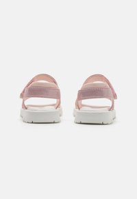 Rosa sandaler med to brede stropper, teksturert overdel, myk fôr og hvit gummisåle med mønster. Åpen bakdesign.