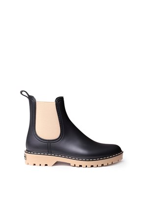 Botte de pluie Chelsea noire avec panneaux latéraux élastiques beige et semelle épaisse beige crantée, montrée de profil sur fond blanc.