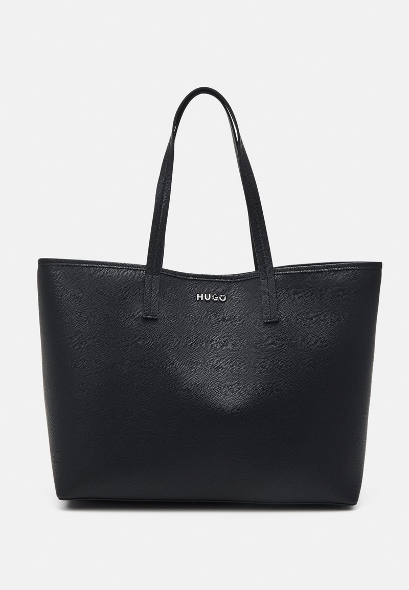 Geantă tote sintetică neagră cu suprafață texturată, două mânere lungi și logo-ul argintiu "HUGO" pe față. Design spațios și structurat.