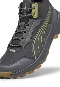 Scarpe da ginnastica nere e grigie con tomaia testurizzata, dettagli verde e suola in gomma flessibile. Presentano un collarino imbottito e lacci.