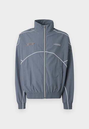 Leichte graue Windjacke mit weißen Akzenten, hohem Kragen, Reißverschluss vorne, elastischen Bündchen und Saum. Mit Logo und Textdetail.