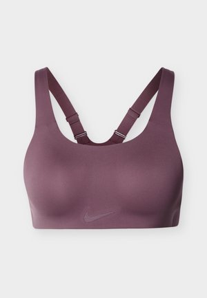 Damski stanik sportowy Nike w głębokim kolorze śliwkowym; gładka tkanina, szerokie ramiączka i krój z wycięciem na plecach typu racerback. Z przodu subtelne logo.