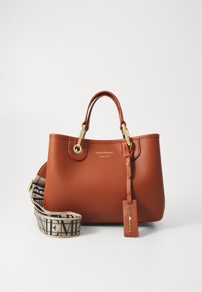 Sac à main en cuir marron avec des ferrures dorées, poignées arrondies et une bandoulière amovible avec un logo à motif. Comprend une étiquette de bagages assortie.