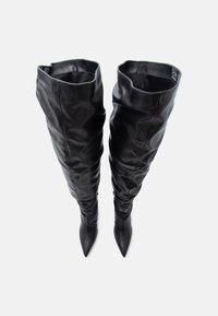 Botas pretas acima do joelho feitas de couro sintético liso, com bico fino, textura franzida e fechos laterais com zíper.