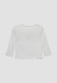 Witte langemouw cropped top met een slabbetje rand op de mouwen en de zoom, weergegeven op een effen lichtgrijze achtergrond.