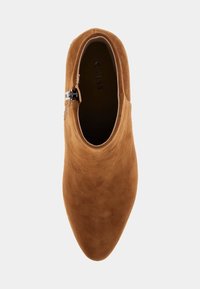 Stivale in camoscio marrone alla caviglia con punta appuntita, dotato di zip laterale e superficie liscia. All'interno presenta il marchio "GUESS" sulla suola.