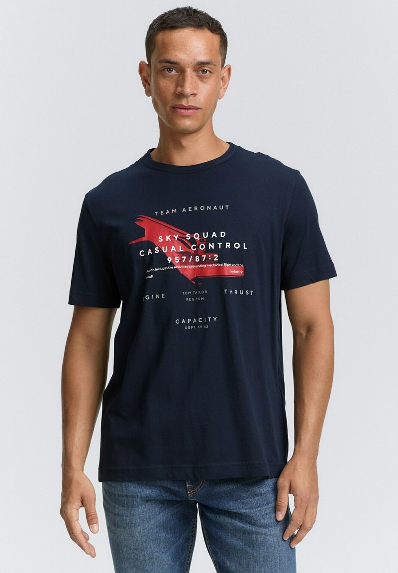 Camiseta de algodón azul marino con texto gráfico en blanco y rojo. Mangas cortas, escote redondo y un corte informal.