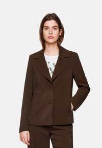 Brauner Blazer aus glattem Stoff. Verfügt über einen Reverskragen, zwei Knöpfe und seitliche Taschen. Leicht taillierte Passform mit sichtbaren Nähten.