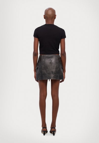 Black cropped t-shirt paired with a grey leather mini skirt featuring pockets and a side zipper. Smooth texture with a subtly worn finish.