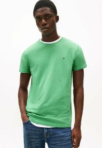 Zielona dopasowana koszulka z okrągłym dekoltem, krótkimi rękawami i białym wewnętrznym kołnierzykiem. Posiada małe logo na piersi i jest wykonana z bawełny.