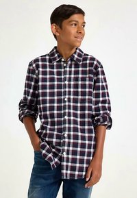 ternet ternet skjorte i marineblå, vinrød og hvid. Bomuldsstof, afslappet pasform, lange ærmer rullet ved manchetterne, enkelt brystlomme.