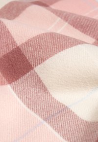 Tkanina w kratę z miękkiej mieszanki wełny, o naprzemiennych odcieniach różu i kremu z subtelnymi niebieskimi liniami, podkreślająca gładkie, teksturowane wykończenie.