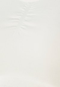 Weißer, dehnbarer Stoff mit einer glatten Textur, der feine Rippungen und gewellte Muster aufweist, die eng den Konturen einer Oberfläche folgen.