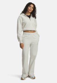 Haut en sweat à capuche crème coupé, avec un zip à l'avant et une poche avant, assorti à un jogging crème ; tissu doux, taille élastique.