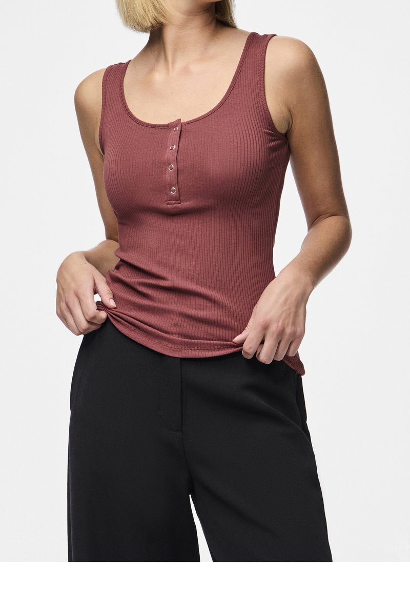 Top senza maniche ribbed color borgogna con scollo rotondo, caratterizzato da una chiusura con bottoni e una silhouette aderente, abbinato a dei pantaloni neri a gamba larga.