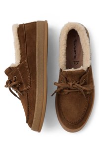 Καφέ σουέτ παπούτσια τύπου slip-on με γούνα εσωτερικά, δέσιμο μπροστά με κορδόνια, καουτσούκ σόλα και ορατό όνομα επωνυμίας στο εσωτερικό ενός παπουτσιού.