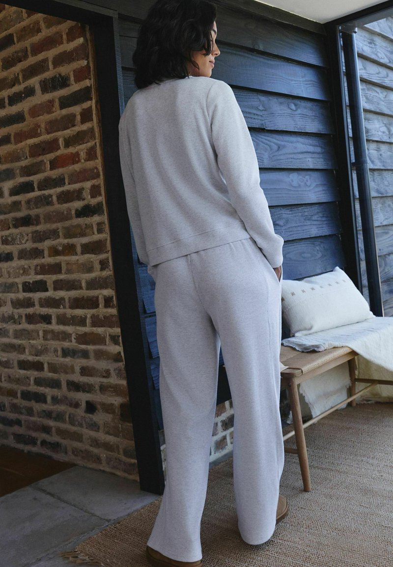 Light gray sweatshirt and matching pants made of soft fabric, featuring a relaxed fit and minimal design, with a ribbed texture.