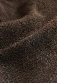 Tela texturizada de color marrón oscuro con variaciones sutiles, que presenta un aspecto suave y tejido, además de un acabado mate.