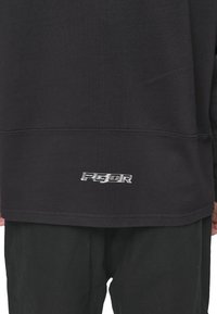 Sudadera negra con ribete en el dobladillo y un logo bordado "PGDR" en blanco en la parte inferior izquierda. Material de algodón suave, ajuste holgado.