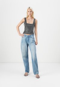 Black and silver sequined crop top with square neckline, paired with light blue, wide-leg denim jeans and black sandals.