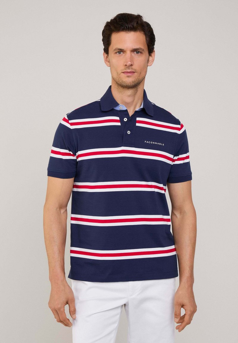 Polo shirt blu navy con strisce orizzontali rosse e bianche, maniche corte e colletto classico. Presenta una piccola tasca etichettata sul petto.