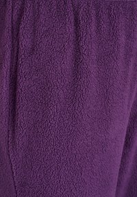 Tissu en polaire violet avec une surface texturée et douce. Le matériau semble agréable au toucher et épais, idéal pour la chaleur et le confort.