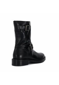 Botte en cuir noir à cheville avec un bout rond, des boucles décoratives et un talon bas empilé. Texture lisse avec un léger éclat.