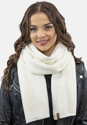 Weißer Strickschal mit strukturiertem, geripptem Muster. Besitzt ein Etikett am Ende. Getragen über einer schwarzen Lederjacke.