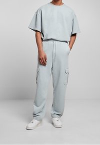 Light blue oversized short-sleeve t-shirt with matching cargo pants. Soft fabric, relaxed fit, elastic waistband, and pockets on pants. White footwear.