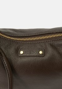 Brown leather bag featuring a textured surface, gold zipper, and a prominent embossed "BRONX" label with two metallic studs.