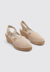 Sandalias de cuña beige con diseño de punta afilada, hechas de suave ante. Cuentan con un tacón envuelto en yute y correas elásticas para mayor soporte.