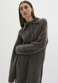 Abito in lana grigia lavorato a maglia, con maniche lunghe, colletto ripiegato e chiusura con bottoni. Presenta una finitura morbida e texturizzata e una vestibilità comoda.