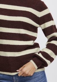 Burgundy és krémszínű csíkos pulóver puha, texturált kötésből. Kerek nyakkivágással és bordázott mandzsettákkal rendelkezik, laza fazonja pedig a kényelmet szolgálja.