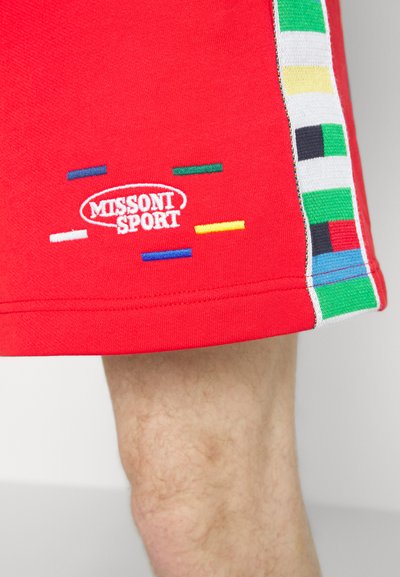 Shorts de sport rouges avec le logo brodé "MISSONI SPORT". Présentent des rayures verticales multicolores sur les côtés et une texture de tissu lisse.