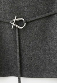 Tessuto di lana grigio con una texture liscia, dotato di una fibbia in metallo argenteo a forma di anello e di un legaccio. Design minimalista con linee pulite.