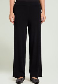 Zwarte wijde broek van een zachte stof, met een elastische taille en een gladde textuur. Het ontwerp bevat geen zichtbare patronen of versieringen.