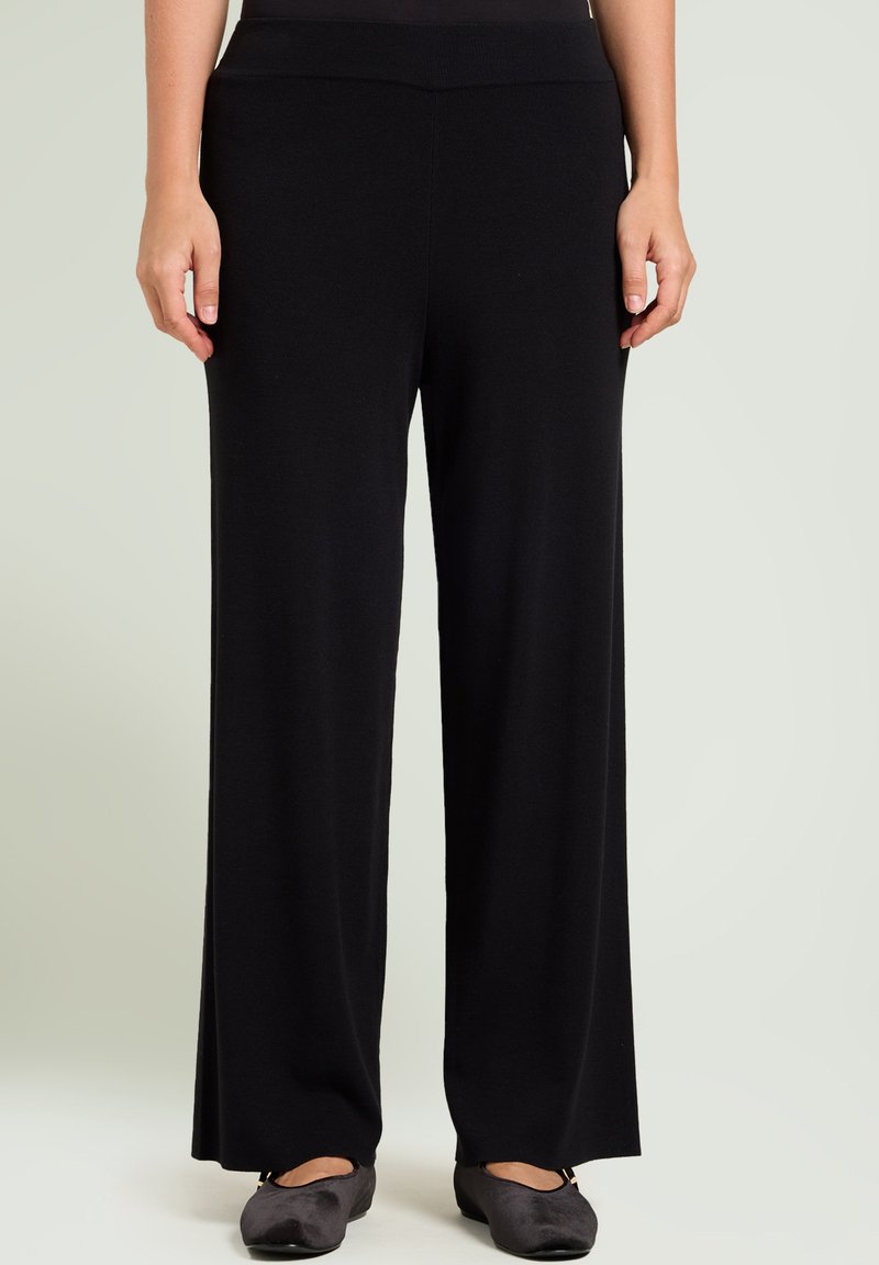 Zwarte wijde broek van een zachte stof, met een elastische taille en een gladde textuur. Het ontwerp bevat geen zichtbare patronen of versieringen.