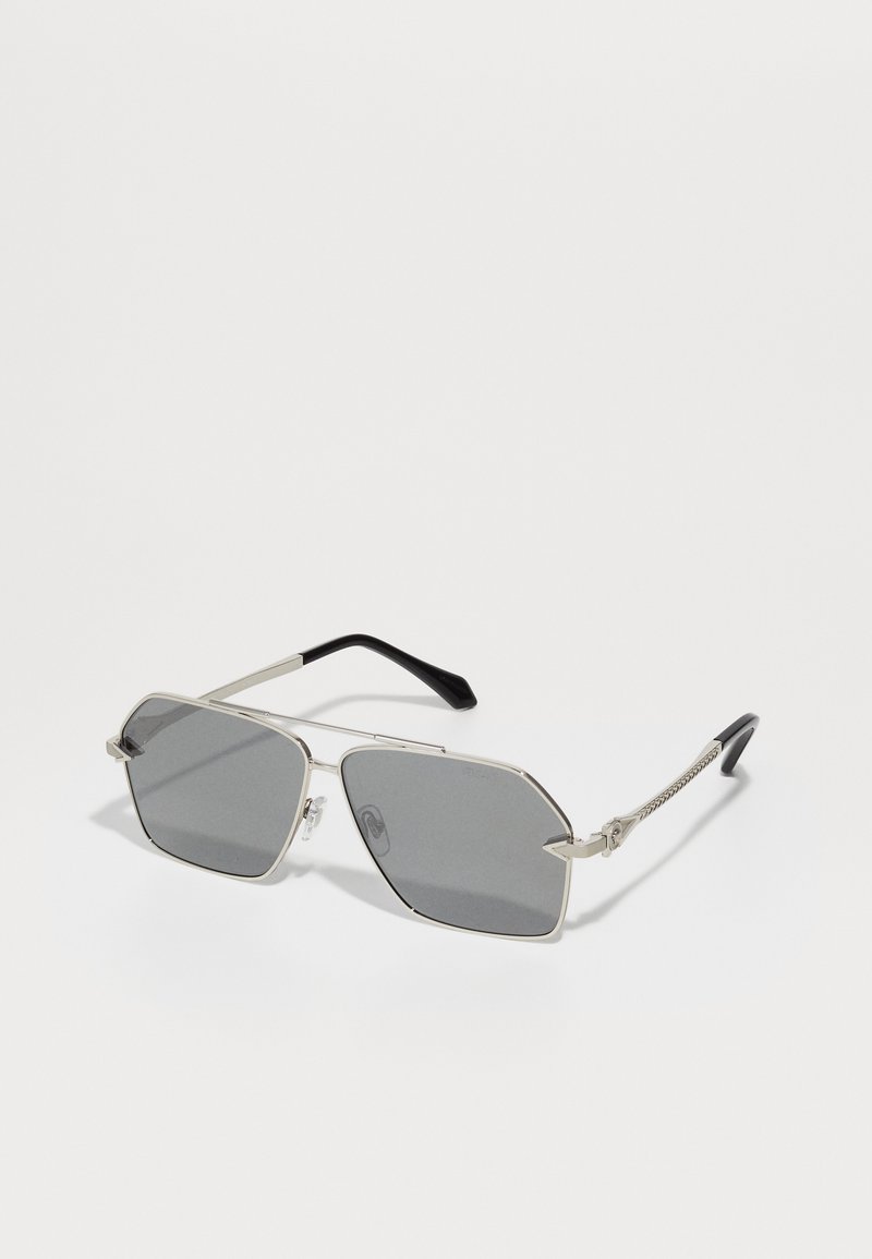 Aurinkolasit, joissa on geometrinen hopeanvärinen metallirunko, tummanharmaat linssit, mustat tempuripäät ja tarkasti muotoillut metallikoristeet sivuilla.