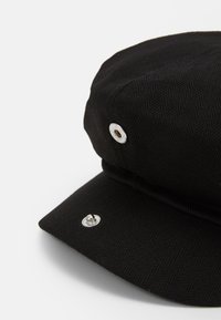 Casquette en chevrons noirs avec une visière plate, dotée de quincaillerie en ton argent, y compris un bouton décoratif et des œillets de ventilation.