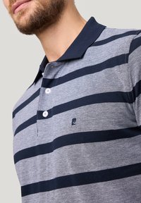 Grau und marineblau gestreiftes Polohemd mit klassischem Kragen, zwei Knöpfen und kleinem Logo auf der linken Brust. Hergestellt aus strukturiertem Stoff.